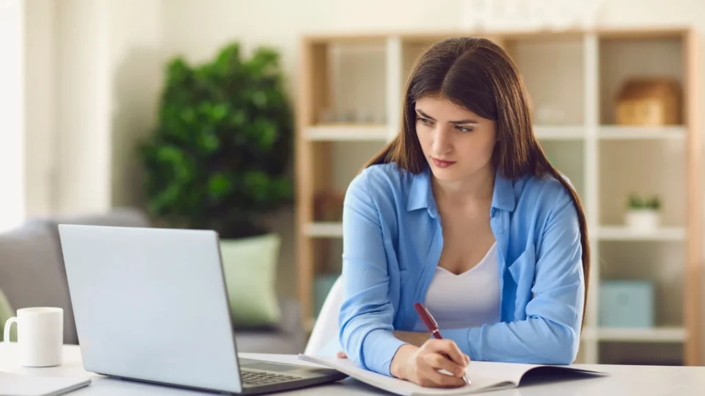 Se observa una mujer tomando notas frente a su laptop, aprovechando un recurso proporcionado por la empresa enfocado en educar